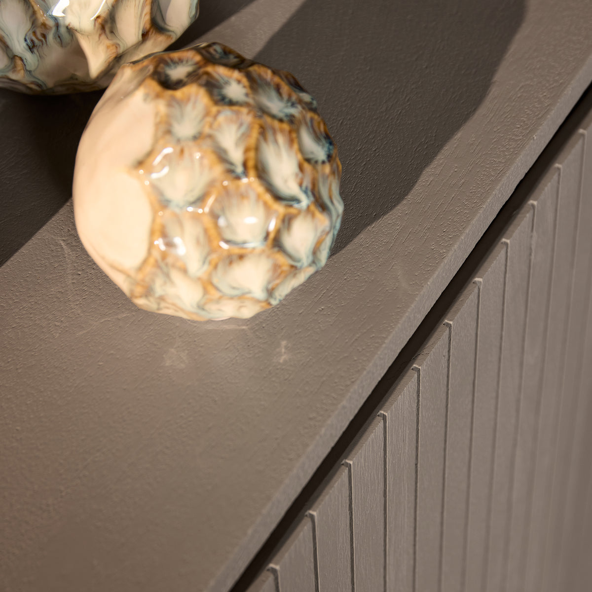 Close up van het blad van dressoir Solana in taupe met decoratie
