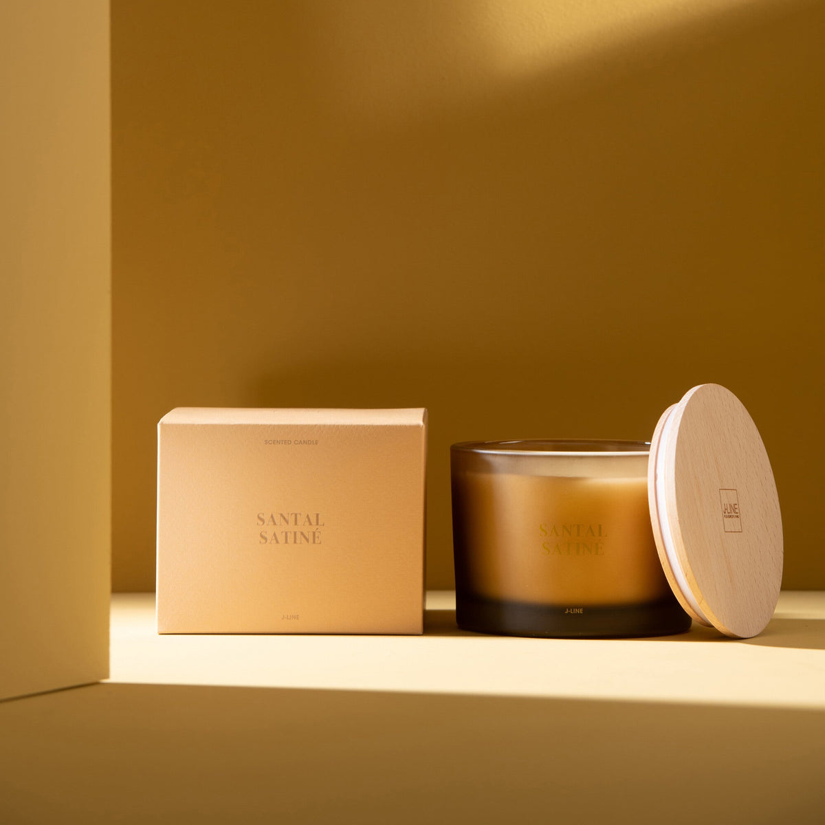 Geurkaars Accords Essentiels Santal Satiné 28 Uur van J-Line met bijpassende doos in een sfeervolle gele setting